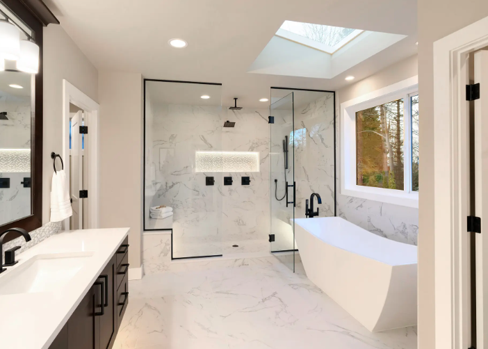 Finished bathroom remodel with freestanding tub, skylight, and marble-look tile