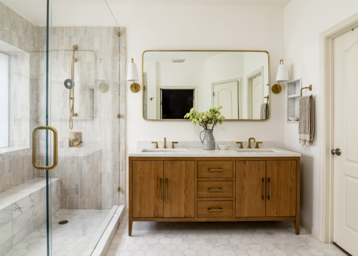 Bathroom remodel with wood vanity, brass fixtures, and glass shower
