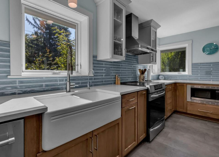 Kitchen remodel with farmhouse sink, blue tile backsplash, and wood cabinetry